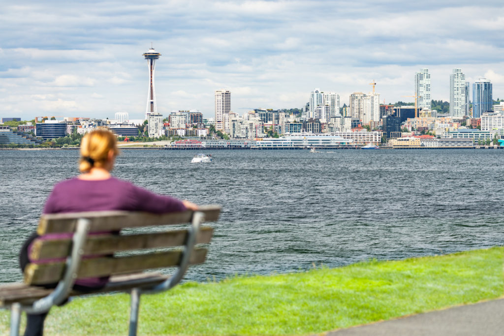 Woman Sitting on Bench Looking At The Seattle, Washington Skyline